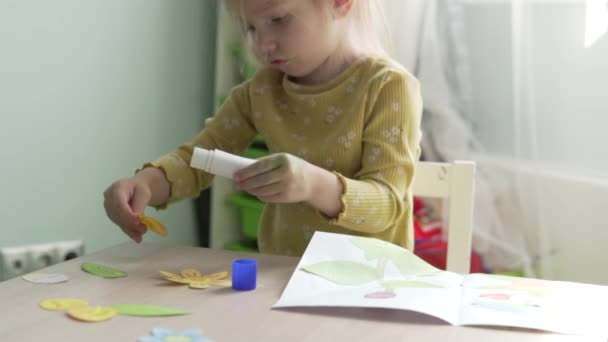 Маленька дівчинка робить квітку аплікації вдома — стокове відео