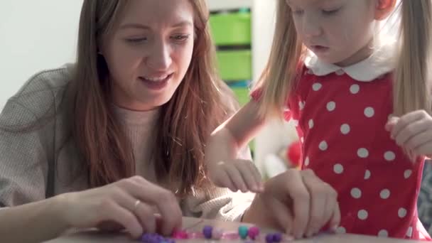 Mamma och dotter gör ett armband av pärlor hemma — Stockvideo