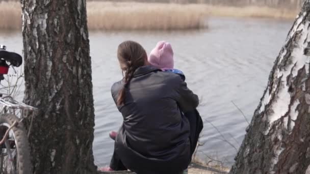 Mãe e filha sentam-se junto ao lago na primavera na Rússia — Vídeo de Stock