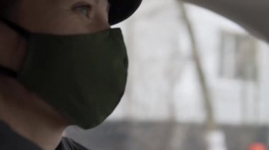 Yüzünde koruyucu maske takan şık bir kadın araba sürüyor.