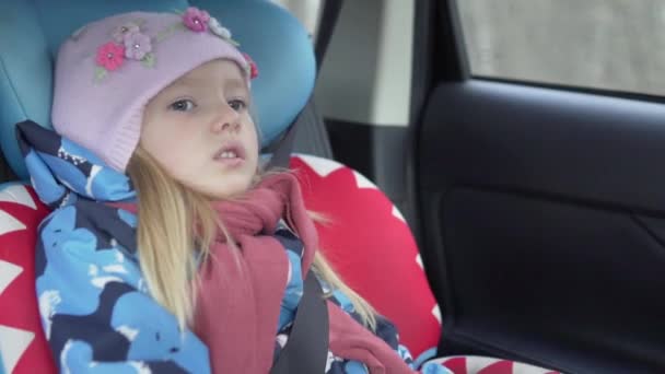 Niña cabalga en un coche en un asiento de coche en primavera — Vídeos de Stock