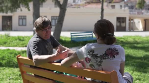 Пожилые люди разговаривают на скамейке в парке во время карантина . — стоковое видео