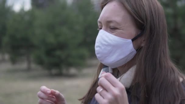 Een vrouw op straat haalt een beschermend masker van haar gezicht en haalt diep adem. — Stockvideo