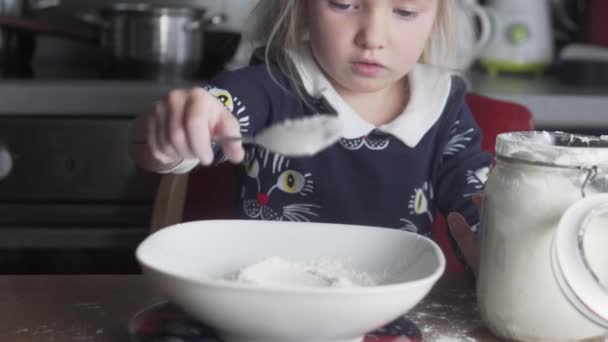 Маленька дівчинка важить борошно на кухонних вагах будинку — стокове відео