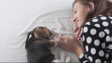 Güzel bir kadın, tatlı bir köpek yavrusuyla yatakta uyuyor..