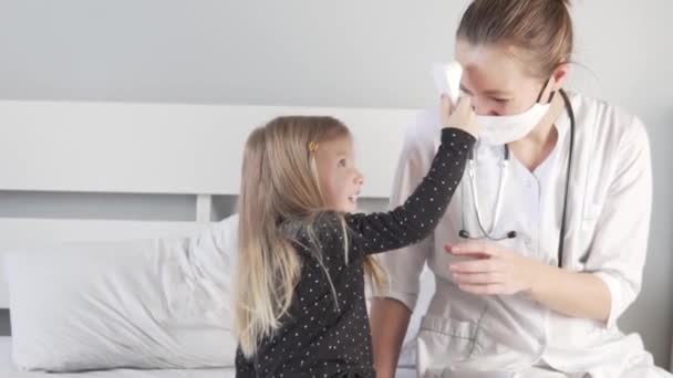 A little girl measures the temperature of a doctor with an electronic thermometer in the hospita — Stock Video