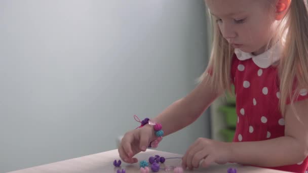 Uma menina bonito faz um grânulo Beads — Vídeo de Stock