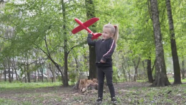 Маленькая девочка запускает в небо игрушечный самолет в небо — стоковое видео