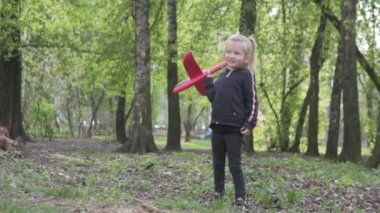 Küçük bir kız oyuncak bir uçağı uçuruyor.