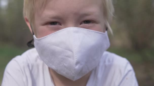 Close-up of a blond boy in a protective medical mask — Stock Video