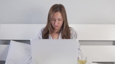 Soğuk algınlığı olan bir kadın bilgisayarda çalışıyor ve limonlu çay içiyor.