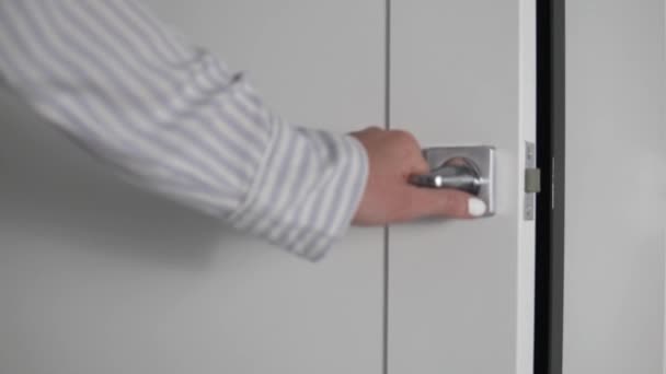 Женская рука закрывает белую дверь за дверной ручкой — стоковое видео