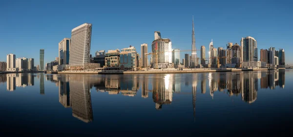 Dubai downtown at day reflected in water.