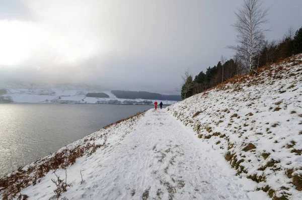 Tourists walking and their foot steps on snowy covered way at Dove stone reservoir, North West England.
