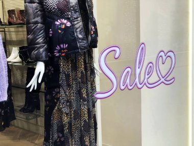 Mağaza vitrininde satış metni. Modern elbiseli bir kadın manken. Kadın modası.