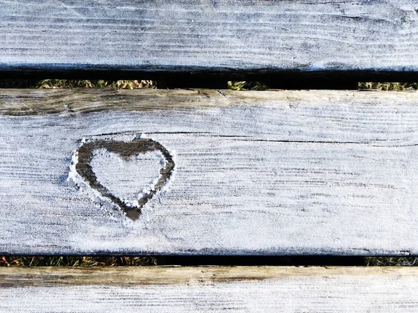 heart drawn on the snow on wooden background. Love concept. Copy space. St. Valentines card