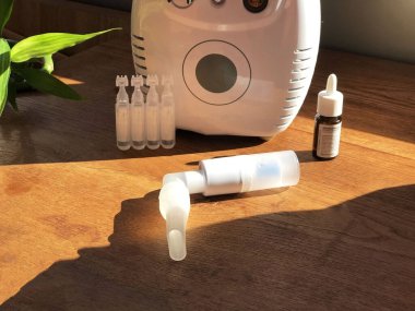 Astım spreyi, solunum cihazları, ilaç şişeleri, ahşap masadaki maske. Solunum tedavisi