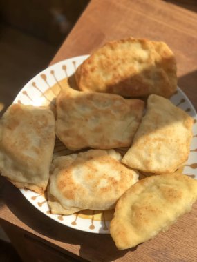 Ahşap masada yakın plan tabakta kızarmış börekler. Cheburek, turta, turta. Ev yapımı yemek.. 