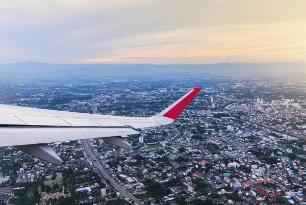 Wing of an airplane flying above the city — Stock Photo, Image