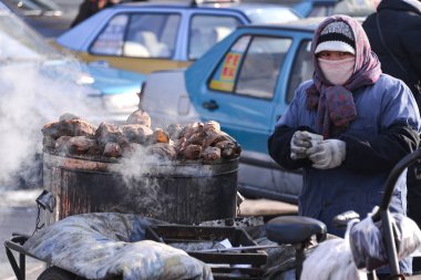 Harbin, China - JAN 20, 2017: Seller selling baked sweet potato on the street. Harbin City, Heilongjiang Province, China. clipart