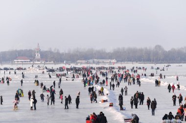 HARBIN, CHINA - JAN 18, 2017: People walking on the frozen Songhua River and There are many activities. January 18, 2017 in Harbin City, Heilongjiang, China. clipart