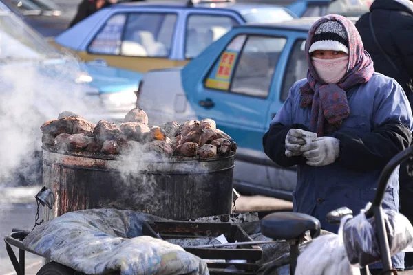Harbin, Çin - 20 Ocak 2017: pişmiş tatlı patates sokakta satan satıcı. Harbin şehri, Çin Eyaleti, Çin.