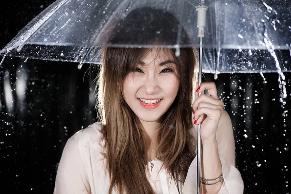 Glückliches chinesisches Mädchen mit Regen und durchsichtigem Regenschirm — Stockfoto