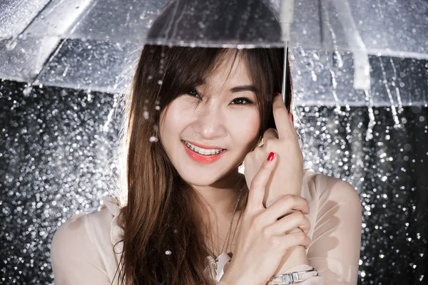 Lycklig kinesisk flicka med regn och genomskinligt paraply — Stockfoto