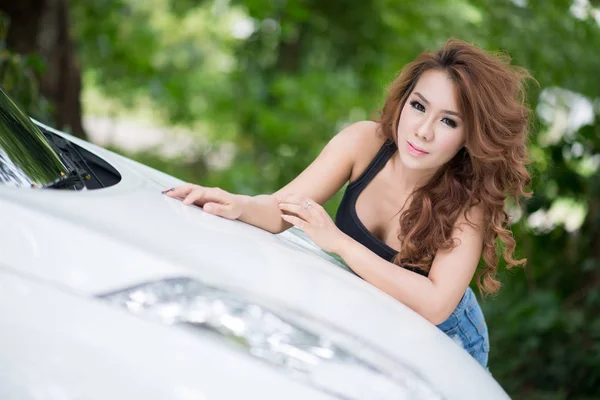 Sexy Mädchen in schwarzer Weste posiert auf Motorhaube Auto — Stockfoto