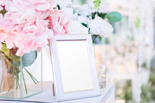 Moldura em branco na mesa e decoração de flores — Fotografia de Stock