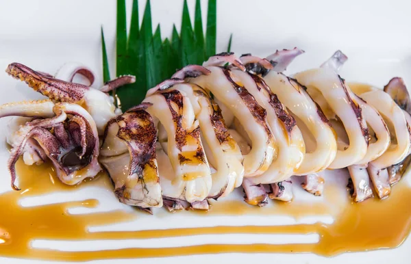 Жареный кальмар с соусом на белой тарелке — стоковое фото