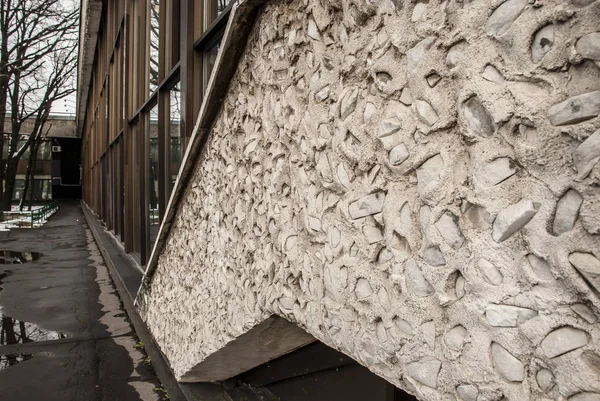 Gri betondan duvar, sert çakıl ve camla kaplı..