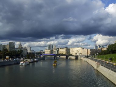 Şehir manzarası, tekneli nehir, bulutlu gökyüzü.