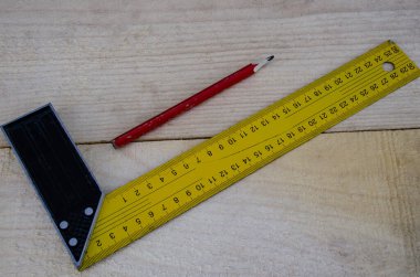 Tahtanın arka planında kırmızı kalem ve sarı cetvel var..