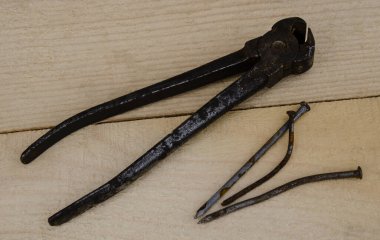 Tahtanın arka planında paslı kıskaçlar ve eğri çiviler var..