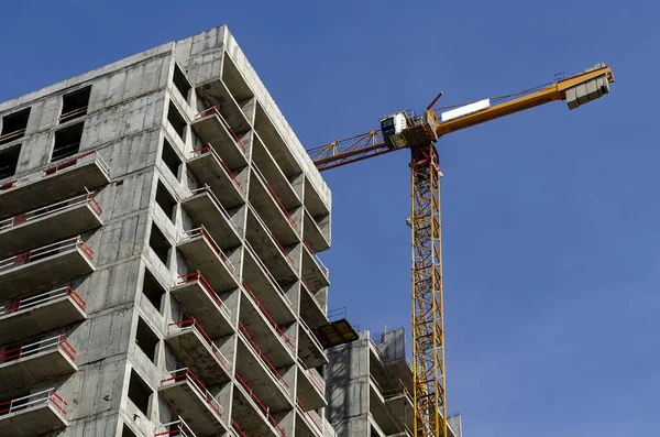 Sarı kule vinci ve mavi gökyüzünün arka planında tamamlanmamış prefabrik ev.