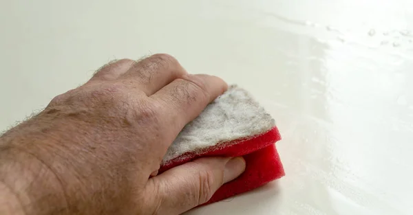 Beyaz bir paneldeki kiri süngerle temizler..