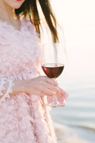 Ein Glas Rotwein Hände eines Mädchens rosa Kleid Haar flattert vom Wind Morgendämmerung Sonnenuntergang Meer Strand Sandwellen — Stockfoto