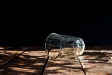 Karanlık bir arka planda boş şeffaf cam. Yatay kahverengi ahşap masa. parlak güneş