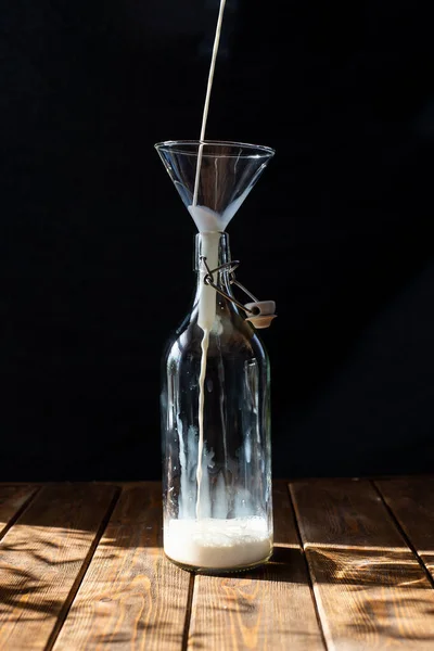 Egy üveg tej egy fa asztalon, sötét háttérrel. Nyakpalack retro közelsége — Stock Fotó