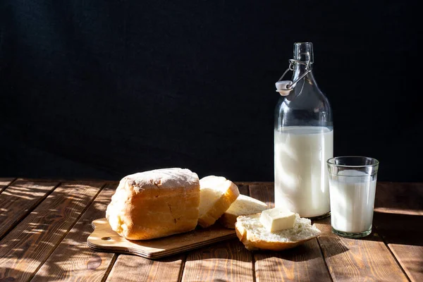 Rustico con pane giallo burro latte tavolo su sfondo nero — Foto Stock