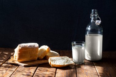 Siyah arka planda sarı ekmek yağlı süt masası olan bir köylü. Kahverengi ahşap arka plan. Doğal arka plan. Yemek arkaplanı. Ev yapımı yemek..