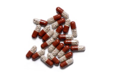 Beyaz arka planda iki tonluk tabletler, içinde granüller olan kapsüller, vitaminler, sağlık hizmetleri. 