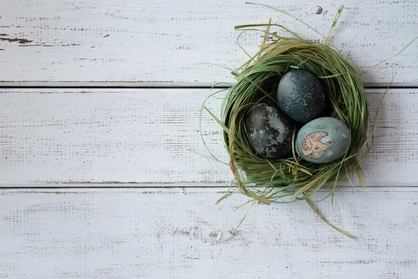 painted eggs for easter. nest of grass. white wooden table
