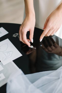 Düğün günü. Gelin alır küpeleri, gelin ücretini, sabah gelini, beyaz elbise, takar küpe.