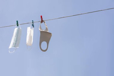 Yıkanmış tıbbi maskeler mavi gökyüzü arka planında kurur.