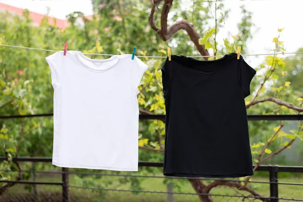 Biało-czarny T-shirt wisi na linie na podwórku i wysycha. — Zdjęcie stockowe