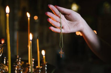 Kadın eli, Hıristiyan haçını ipte tutuyor. Kilise içeride. Akşam oldu.