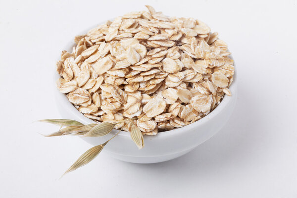 oat flakes in a bowl with ears, isolated