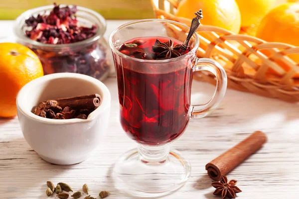 Vino caliente Karkade té, con una insignia y cardamomo en un vaso sobre una mesa de madera naranja — Foto de Stock